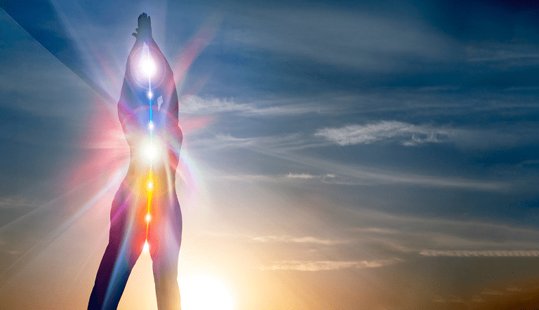 2 Silhouette of a person with hands raised above head, overlaid with seven colorful lights along the spine, against a sunset sky.